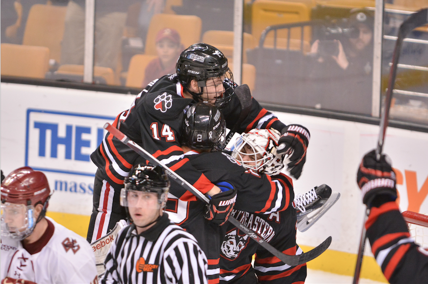 Several Northeastern Husky players leap onto each other after they won the Beanpot semifinals against Boston College.