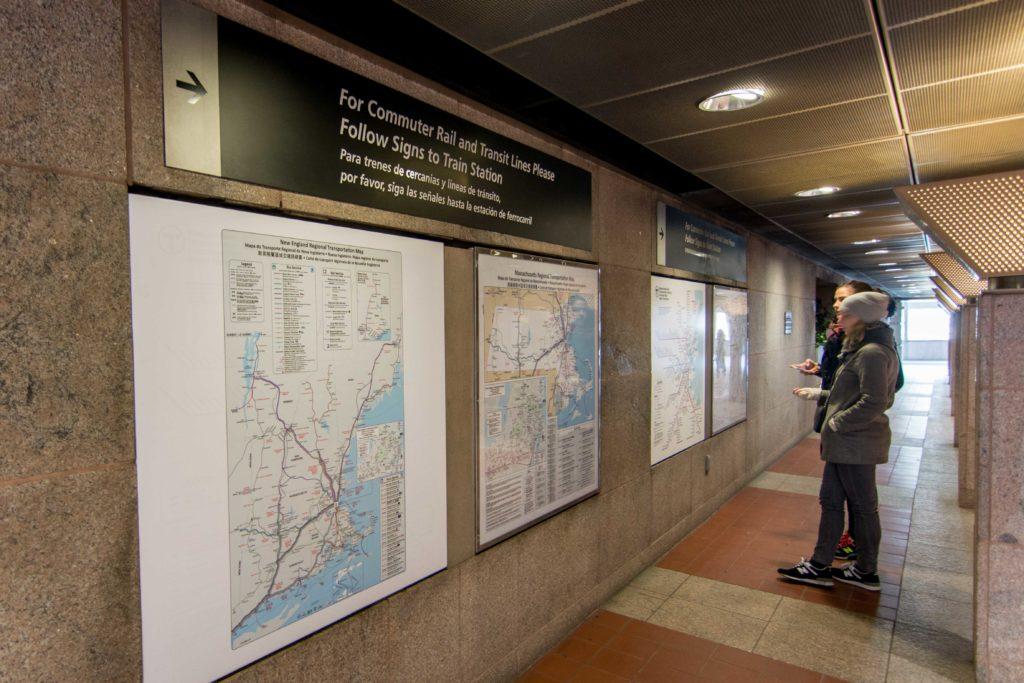 New commuter rail and transit line maps, pictured here with commuters at South Station, will soon replace older maps at MBTA stations across the city. Photo by Joe Thomas.