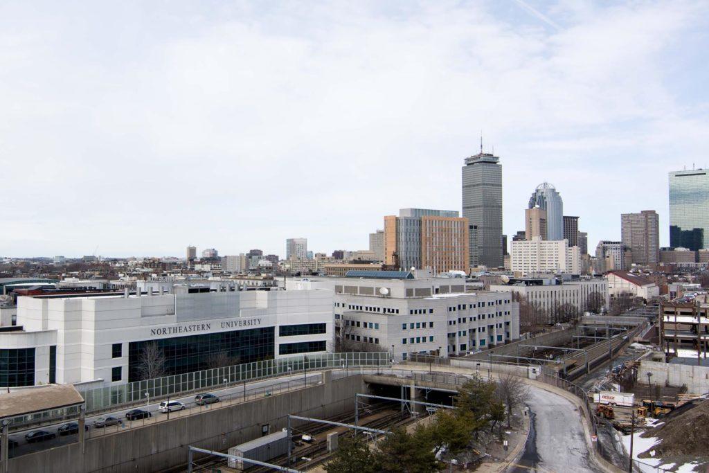 After initially refusing to pay the $2.5 million the City of Boston requested in lieu of taxes for the 2014 fiscal year, Northeastern has paid $886,000. It is one of 15 universities that has not paid the full requested amount. Pictured: Northeastern with a backdrop of Boston's skyline. Photo by Joe Thomas.