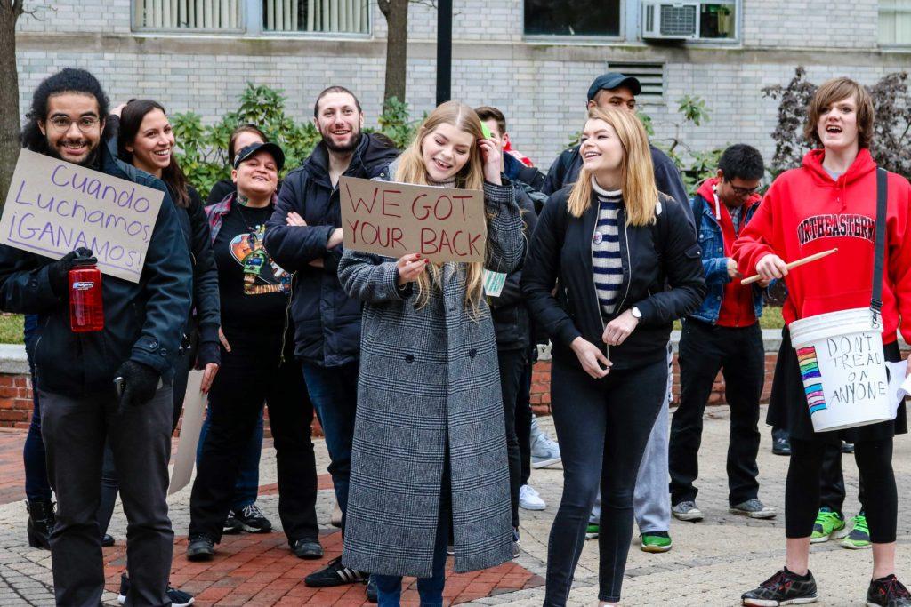 Students gather in the library quad holding signs and showing their support for workers and minority groups.