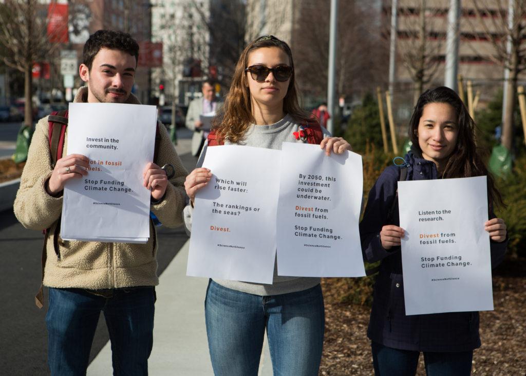 Members of DivestNU hold posters and hand out flyers outside the ISEC building as guests arrive. / Photo by Dylan Shen