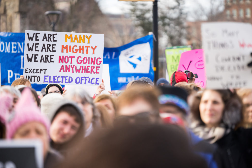 Signs at the Women's March in Cambridge. This sign reads, “We are many, we are might, we are not going anywhere, except into elected office.” / Photo by Alex Melagrano.