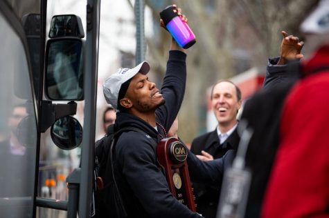 Junior forward Shawn Occeus brings the CAA trophy off the bus Wednesday.