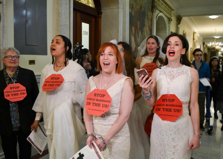 Rep. Kay Khan, Tammy Monteiro, Alex Boyer-Coffey, Amanda Parker and Fraidy Reiss sing in front of Gov. Charlie Baker’s office.