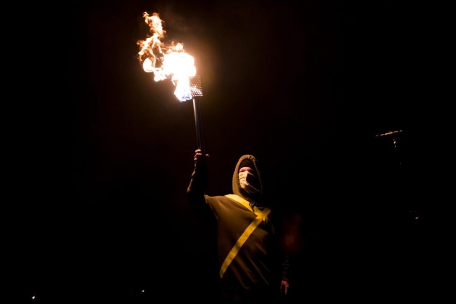 Josh Dun of Twenty One Pilots walks on stage at the start of the performance holding a torch.