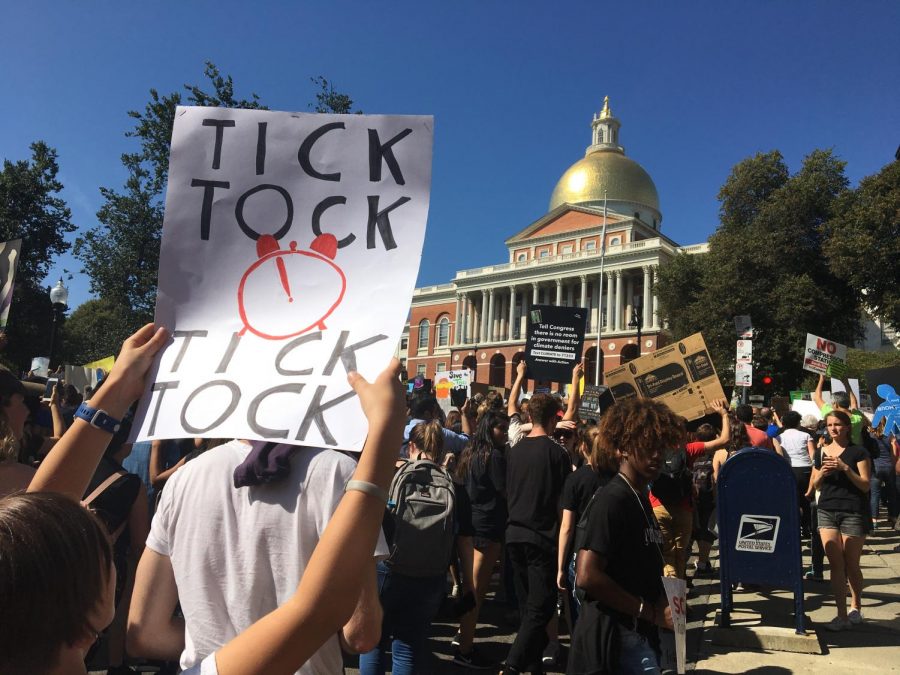 A demonstrator taking part in the Global Climate Strike holds up a sign outside the State House. 