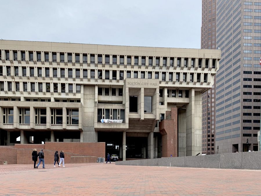 Pedestrians pass through City Hall's expansive brick plaza on a cloudy day.