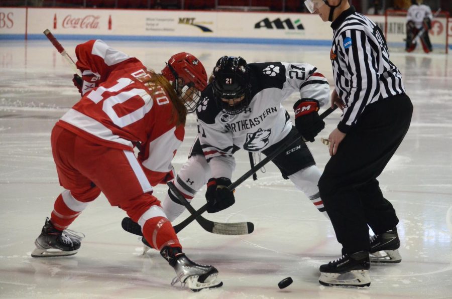 Northeastern and Boston University face off against each other to gain possession of the puck. 