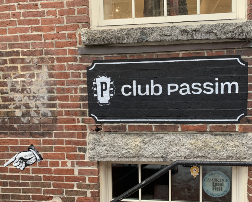 A sign painted on the brick wall marks the entrance to Club Passim on Palmer St. Photo credit Jane Clements. 