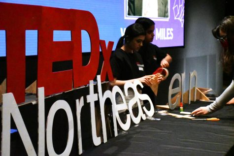 Members of the TEDxNortheasternU team set up stage in the auditorium of ISEC.