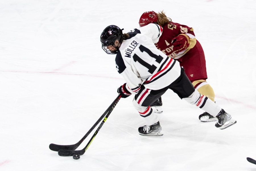 Graduate student forward Alina Mueller battles for the puck. Mueller assisted on the games sole goal to put the Huskies over the top.