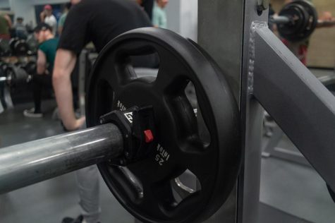 A 25-pound weight plate rests on a bench press in Marino Recreational Center. Alexis Algazy has discovered the mental benefits of weightlifting have become more important to her than the physical results.