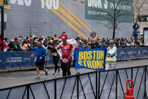 Two people hold a “Boston Strong” sign while running. The “Boston Strong” slogan emerged following the 2013 bombing, symbolizing the city coming together in the aftermath.