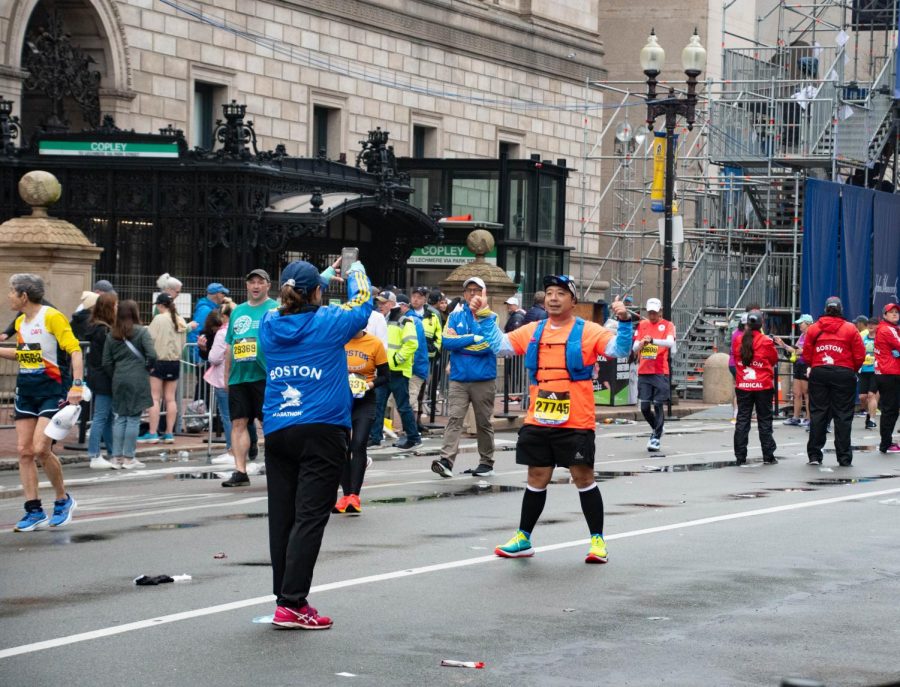 A runner smiles and gives a thumbs up as a volunteer takes his picture in front of the finish line. #BostonMarathon was one of several hashtags used to share content surrounding the race online.