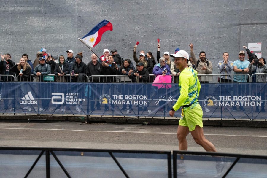 A man smiles as spectators wave the Philippine flag and ring cowbells in the background. Approximately 120 countries were represented in this year’s marathon.