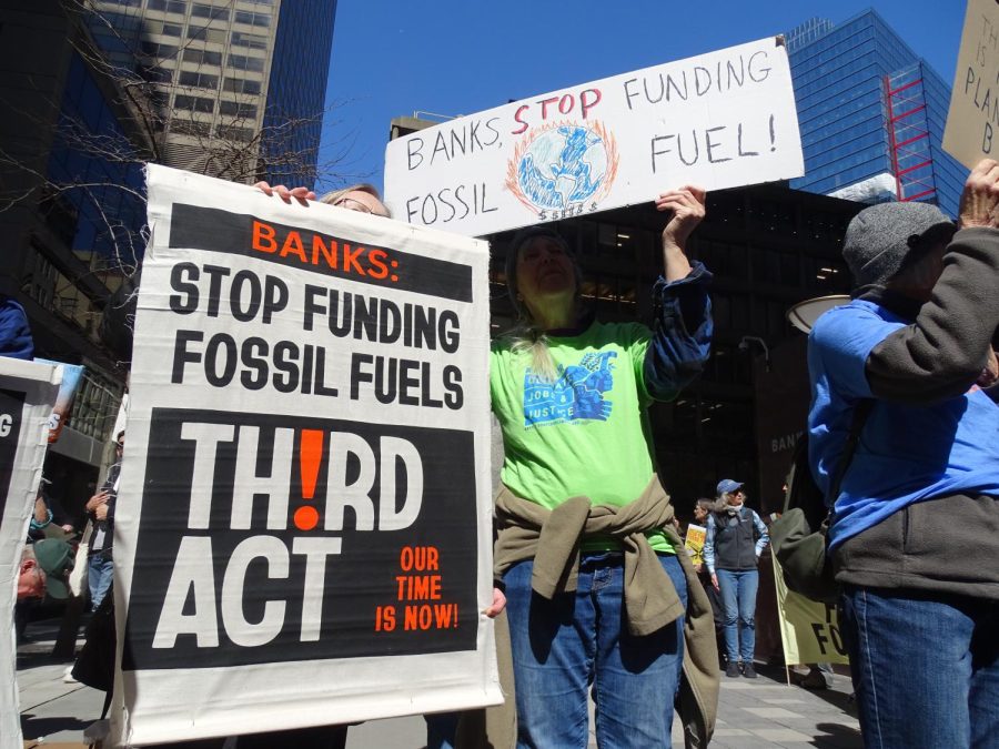 Demonstrators hold up signs outside Chase Bank and Bank of America in downtown Boston March 21. Environmental activists called for people to divest from banks with ties to the fossil fuel industry.