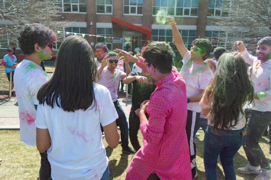 Students dance to music and throw colored powders in the air.