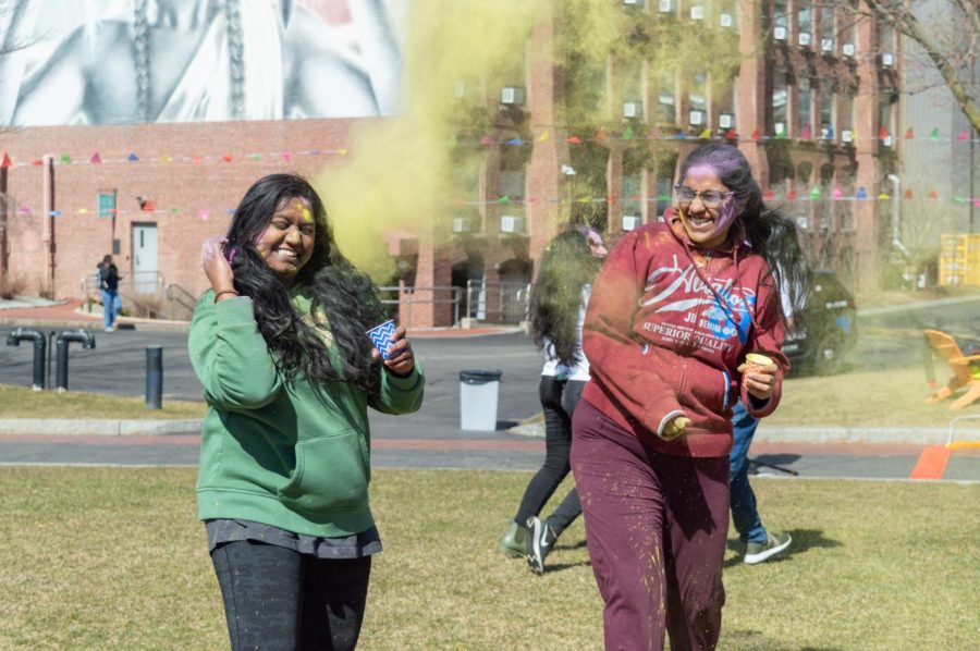 Two attendees smile while being hit with green powder.