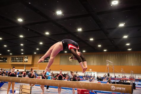 First year Katie Burke performs a backflip on a balance beam at a national competition in Memphis, Tennessee, March 29. GymNUstics placed seventh at the meet.