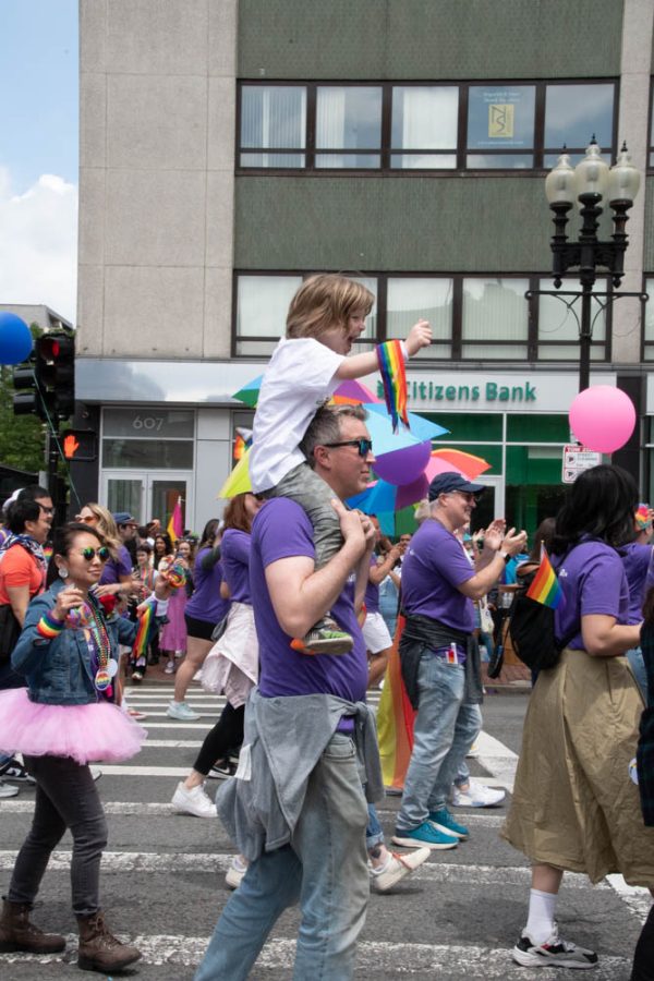 A child with a rainbow ribbon sits atop an adult’s shoulders. The parade and audiences were filled with families celebrating Pride together.