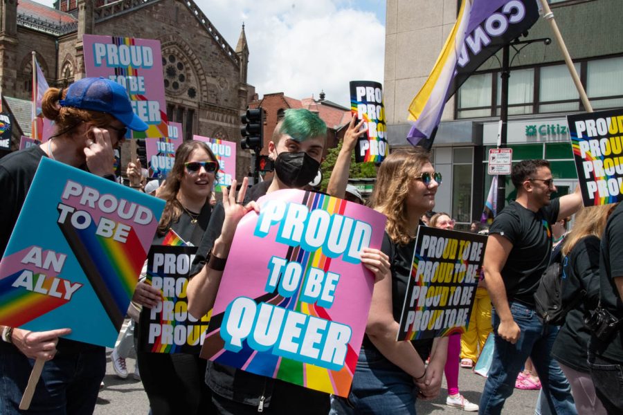 A Converse employee holds a sign that says, “Proud to be Queer.” Converse gave out rainbow shoelaces to spectators during the parade.