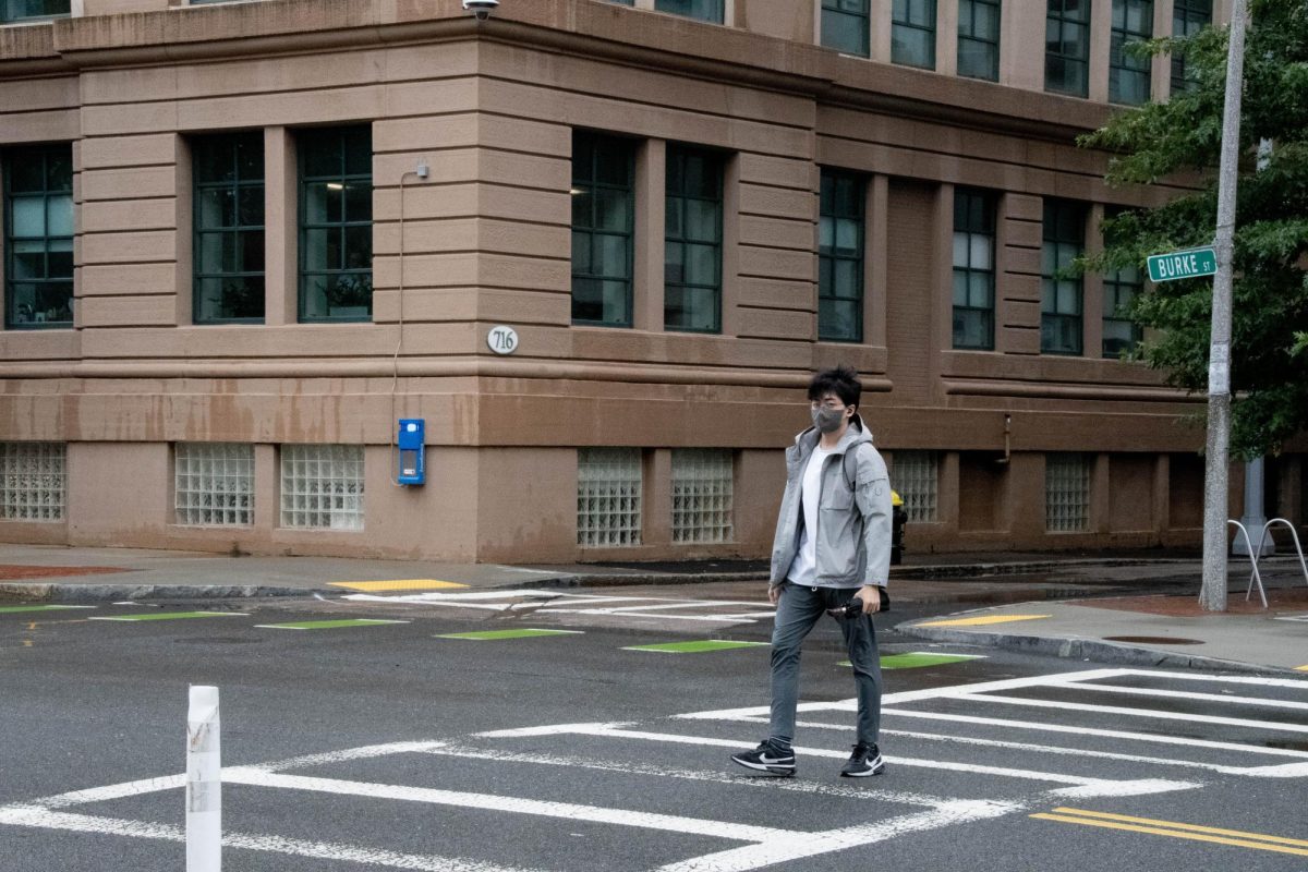 A man wearing a rain jacket and carrying an umbrella crosses Columbus Avenue. With the increased precipitation this summer, many cites saw storm drain issues and increased flood risks.