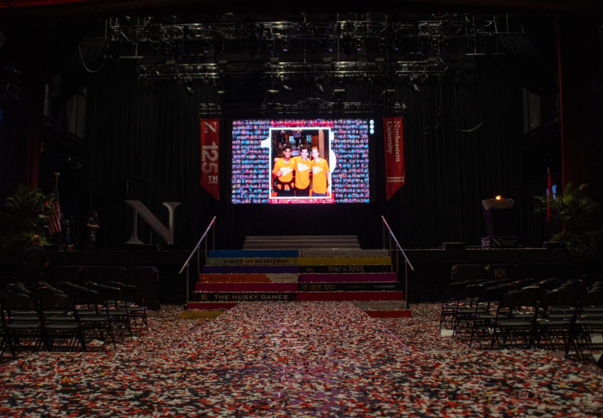A screen displays photos of the incoming class in front of a confetti-covered floor. Aoun encouraged the class of 2027 to explore all that Northeastern has to offer, including the global opportunities that the school provides.