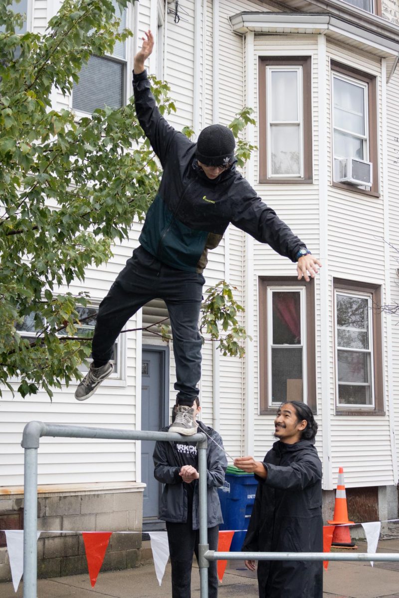 A member of Parkour Generations Boston demonstrates walking backward on a wet metal bar with some ground support from a teacher. Parkour Generations Boston set up an obstacle course for kids to learn basic parkour moves during the festival.