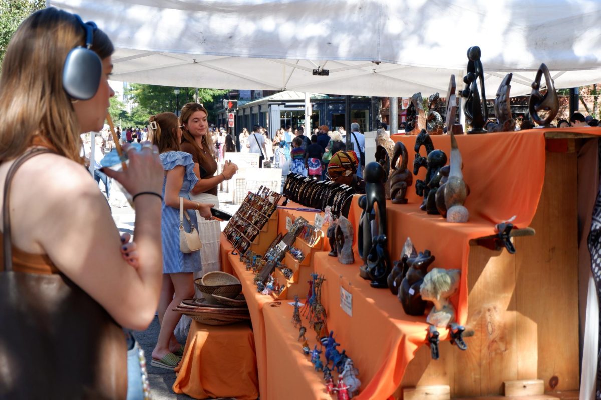 Passersby look at a variety of figurines and jewelry being sold at a tent. Businesses with locations along the street were encouraged to set up tents, and the City of Boston also allowed pop-up businesses to apply for a tent.