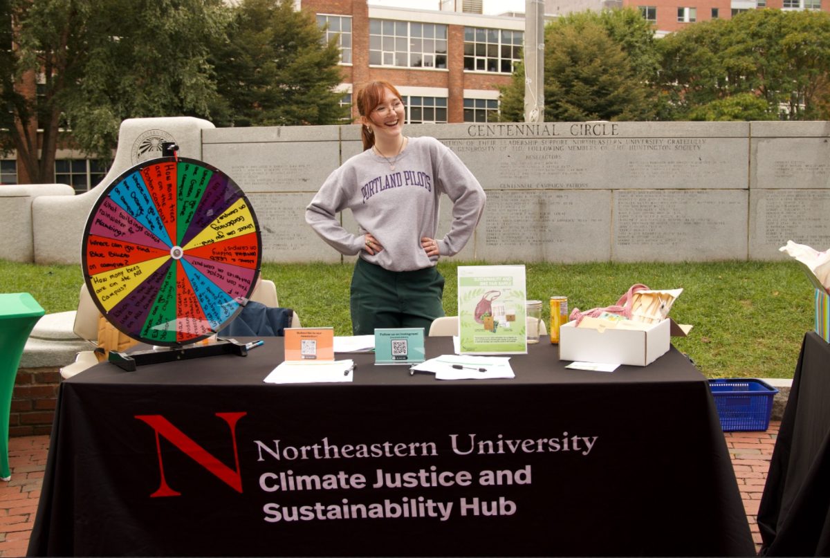 Bridget McClarnon, a Northeastern Climate Justice and Sustainability Hub co-op, shows off the organization’s raffle prize and education wheel of questions. Students who spun the wheel were given the chance to answer questions about sustainability on campus and learn more about sustainable efforts at Northeastern.
