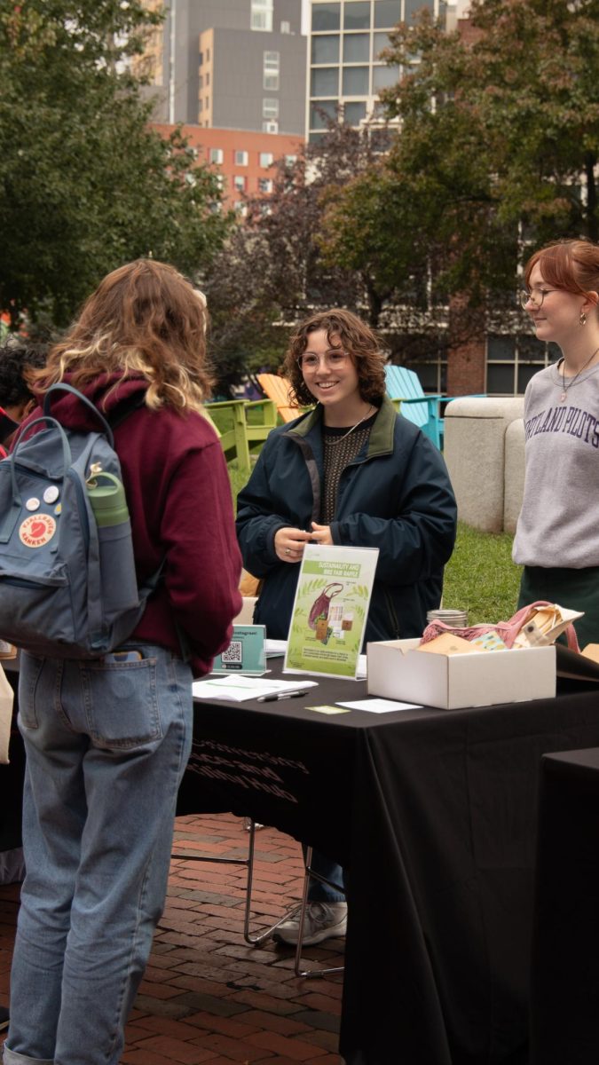 A student engages with the Northeastern Climate Justice and Sustainability Hub table. The climate justice hub co-ops attended the event and educated people on their sustainability efforts, such as the connections they create with different faculty and organizations in order to keep Northeastern sustainable.