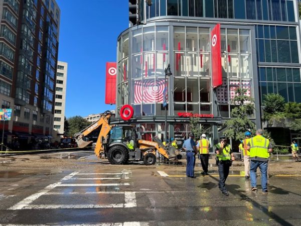 Boston police and Boston Public Works employees gather around the burst fire pipe that serviced the Fenway Target. Utility workers had to dig under the street in order to find and repair the source of the break.