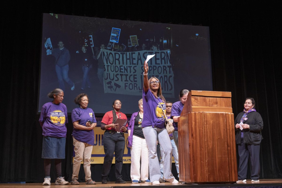A+member+of+the+32BJ+union+raises+her+hand+in+front+of+a+screen+showing+Northeastern+students+support+for+janitorial+workers.+Northeasterns+facilities+were+cleaned+by+members+of+the+32BJ+union.+Photo+courtesy+Ann+Hermes.