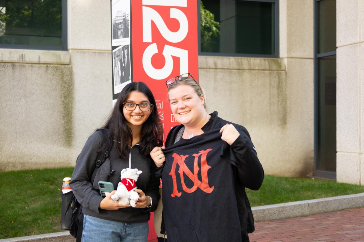 Two people pose while holding a stuffed husky plush and a custom screen printed t-shirt. Multiple pop-up activities were spread around campus.