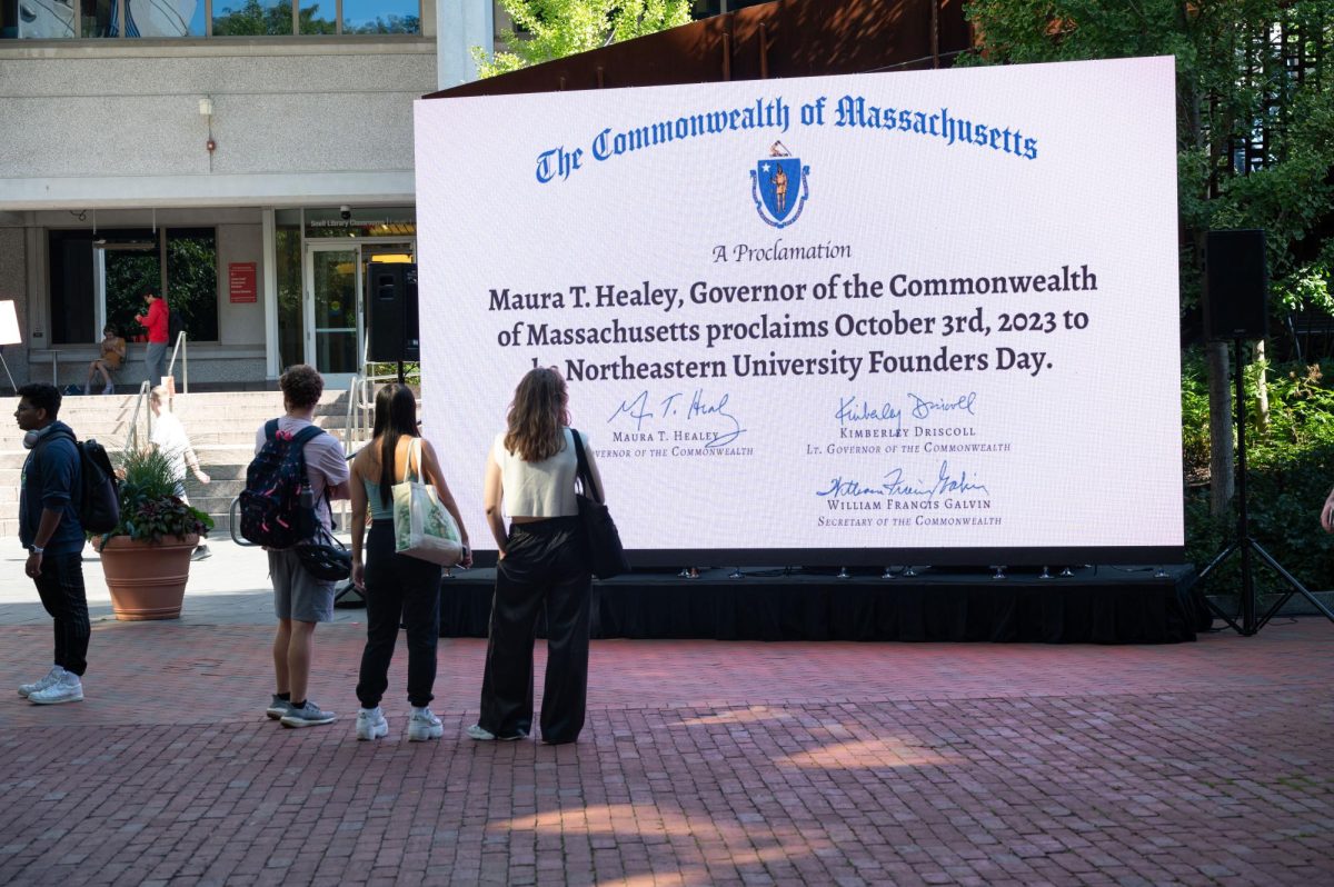Students look at a screen display showing Maura Healeys declaration of Oct. 3 as Northeastern University Founders Day. This further cemented Northeasterns historical significance as a university in Massachusetts.