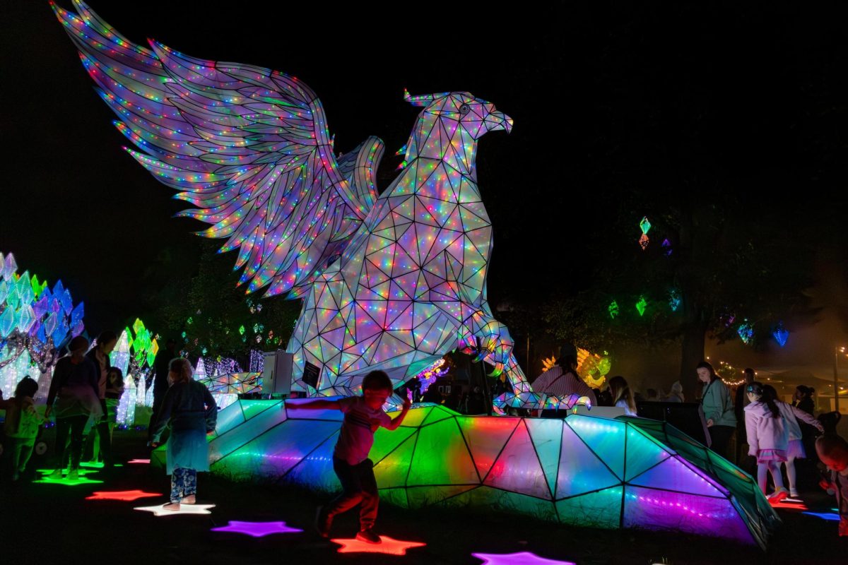 Children hop on color changing star jump pads that surround a griffin lantern. The griffin was in the clearing along with the food vendors, allowing parents to relax with food while their families enjoyed the nearby activities.