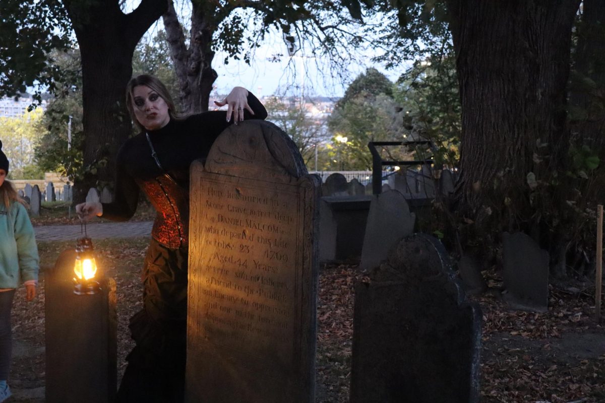 Tour+guide+Scarlet+Gray+tells+the+haunted+story+of+the+deceased+under+the+tombstone.+The+tour+offered+participants+the+opportunity+to+walk+through+Boston%E2%80%99s+17th+century+graveyards.
