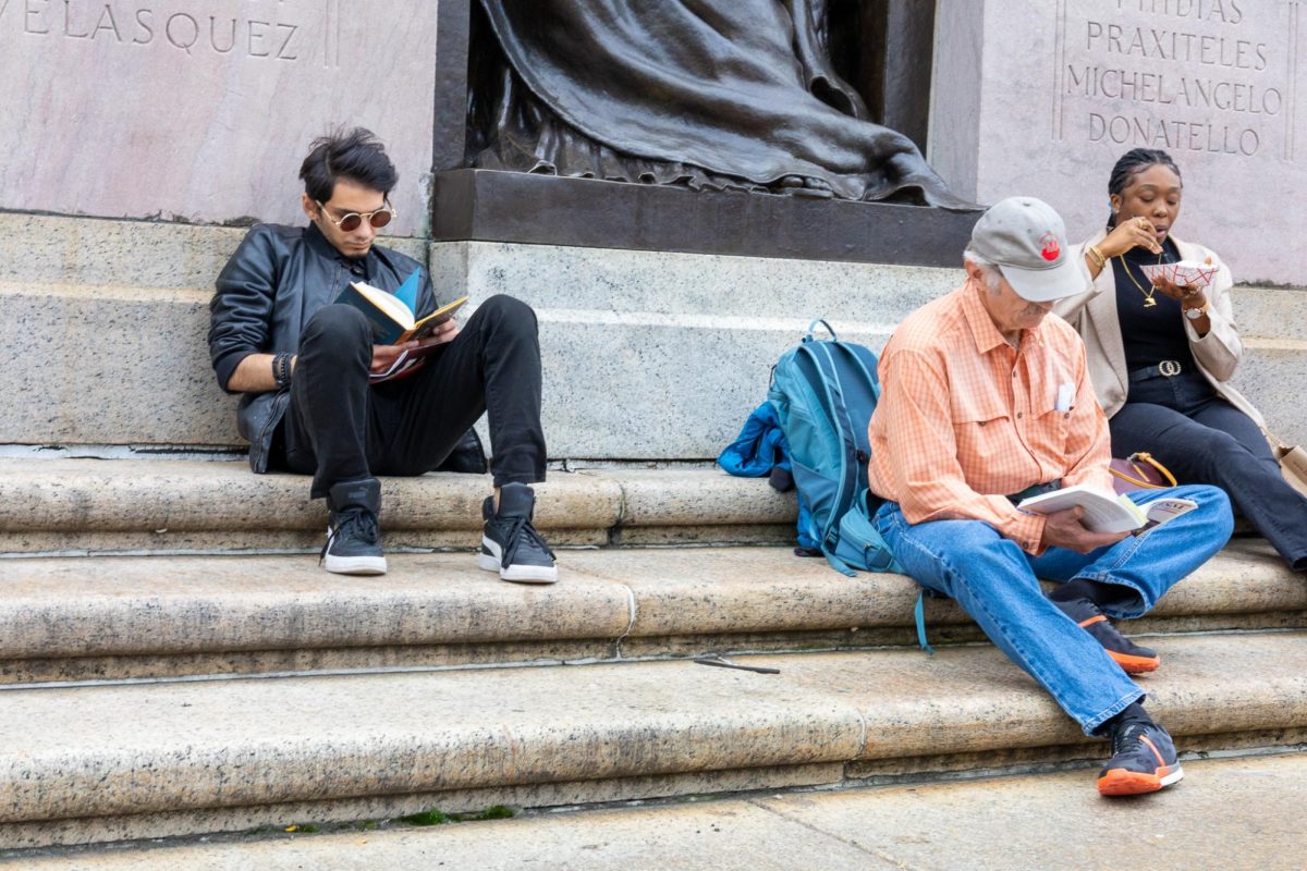 Two people read books while sitting on the steps of the Boston Public Library. A large collection of $5 books were sold at the festival.