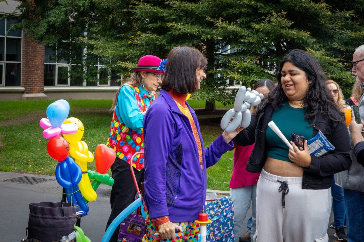 A member of the event staff hands a balloon animal to a Family & Friends Festival attendee. Participants were able to choose which kind of balloon they wanted.