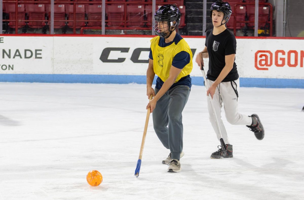 A Cherrybombs player eyes for an open teammate to pass to in hopes of scoring a goal. Similar to ice hockey, Broomball players could not high stick, kick the ball or carry the ball; however, if the ball was shot into the air, players were allowed to swat it down using their hand.