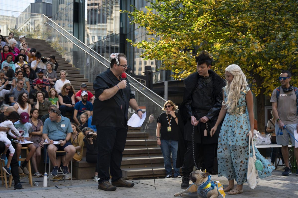 A dog in a dragon costume and his family, dressed as “Game of Thrones” characters, are introduced to the audience. Following the parade, the event host introduced each dog to the judges.