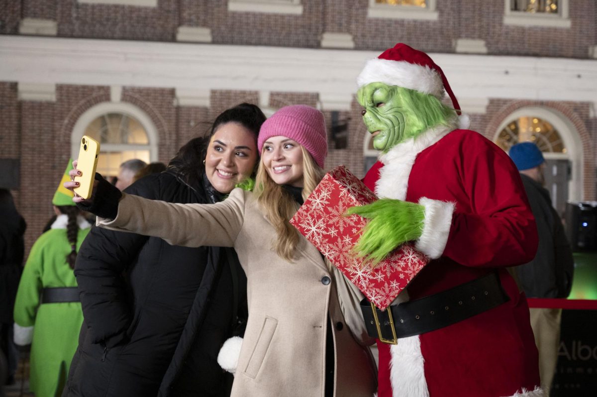 Two people pose for a selfie with someone dressed as the Grinch. Children and adults alike lined up for a photo with the Grinch.