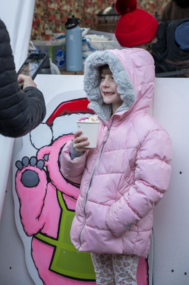 A child smiles while holding a cup of ice cream as her mother takes a photo. Despite the chilly weather, many purchased frozen treats.