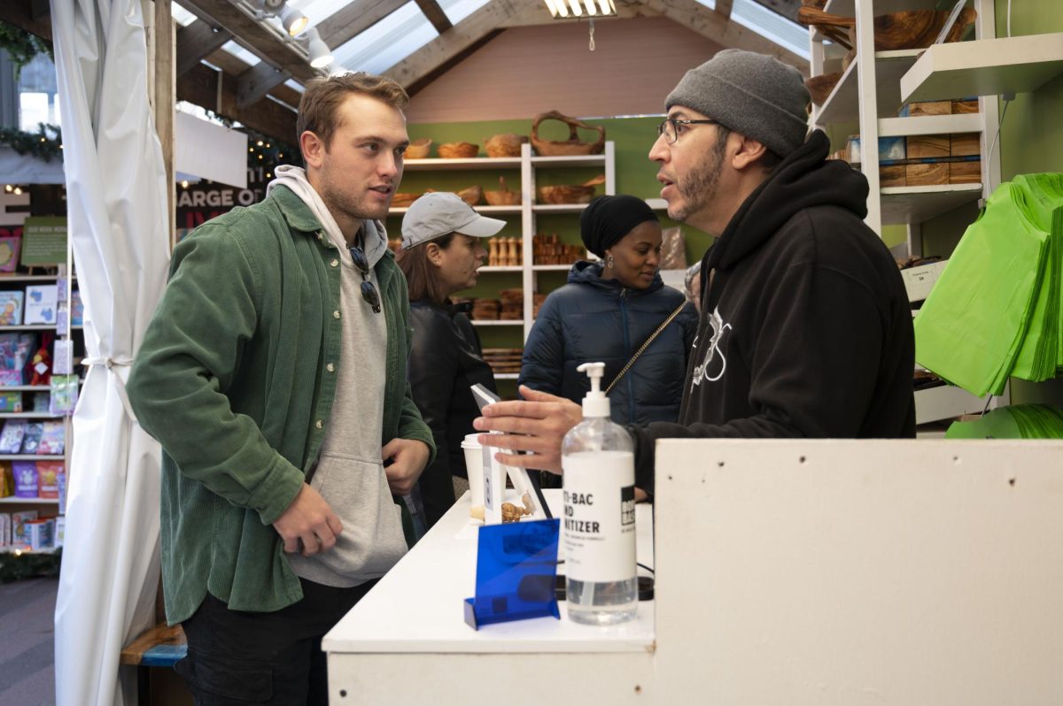 A vendor for  Natural OliveWood talks to a customer. Like many vendors, the booth sold handmade goods.