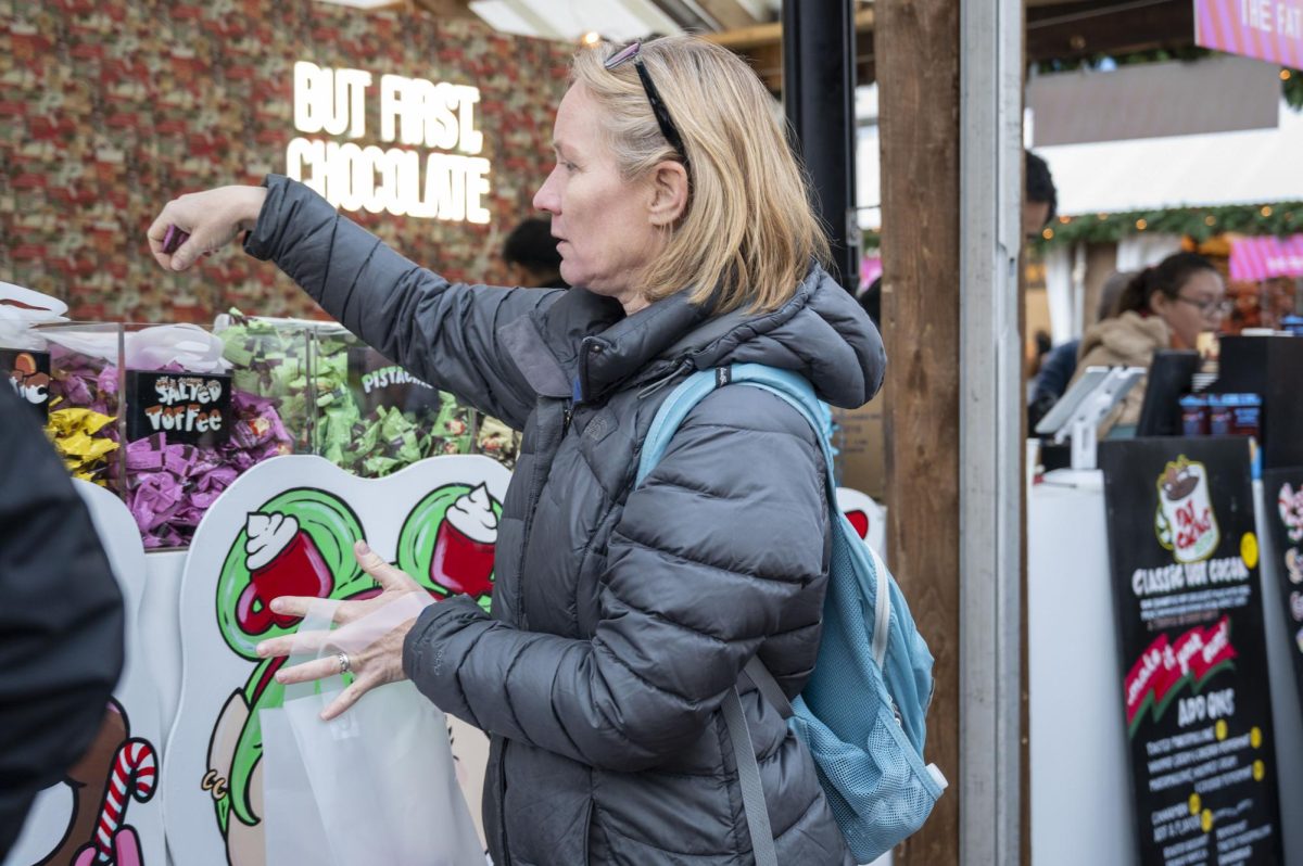 A woman reaches for salted toffee from  The Fat Cactus. Along with various chocolates, the booth served specialty hot chocolate drinks.