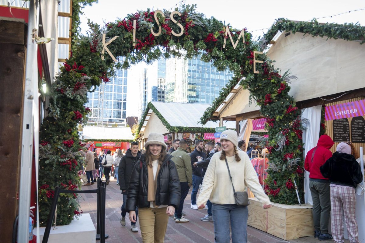 Two women walk under an archway that says “Kiss Me.” Decorations such as wreaths, Christmas trees and string lights contributed to the holiday atmosphere.