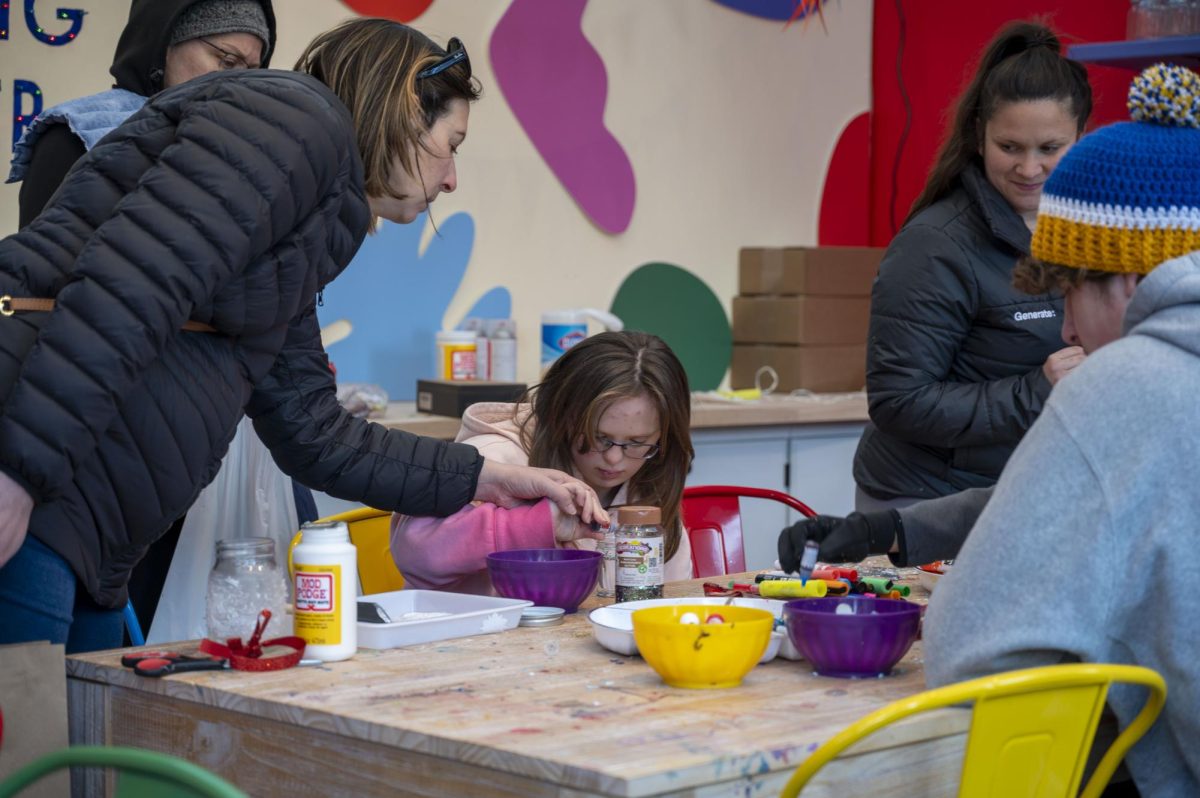 A mother helps her child with a craft. Located near the food and drink lounge, The Holiday Market featured a “Crafting Corner” where children could do arts and crafts.