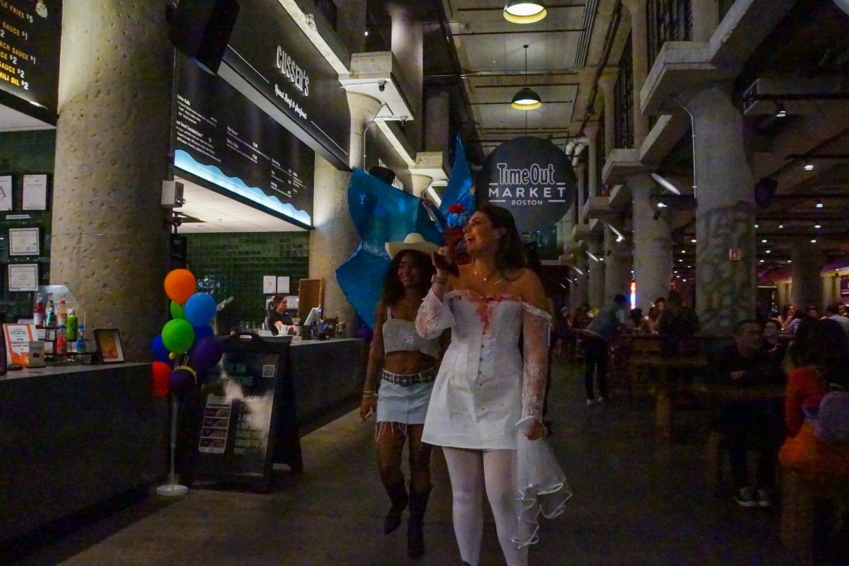 Market attendees look at restaurant menus while a stilt walker walks behind them. Time Out Market kept its restaurants open for the late-night event, drawing hundreds of Halloween celebrants.