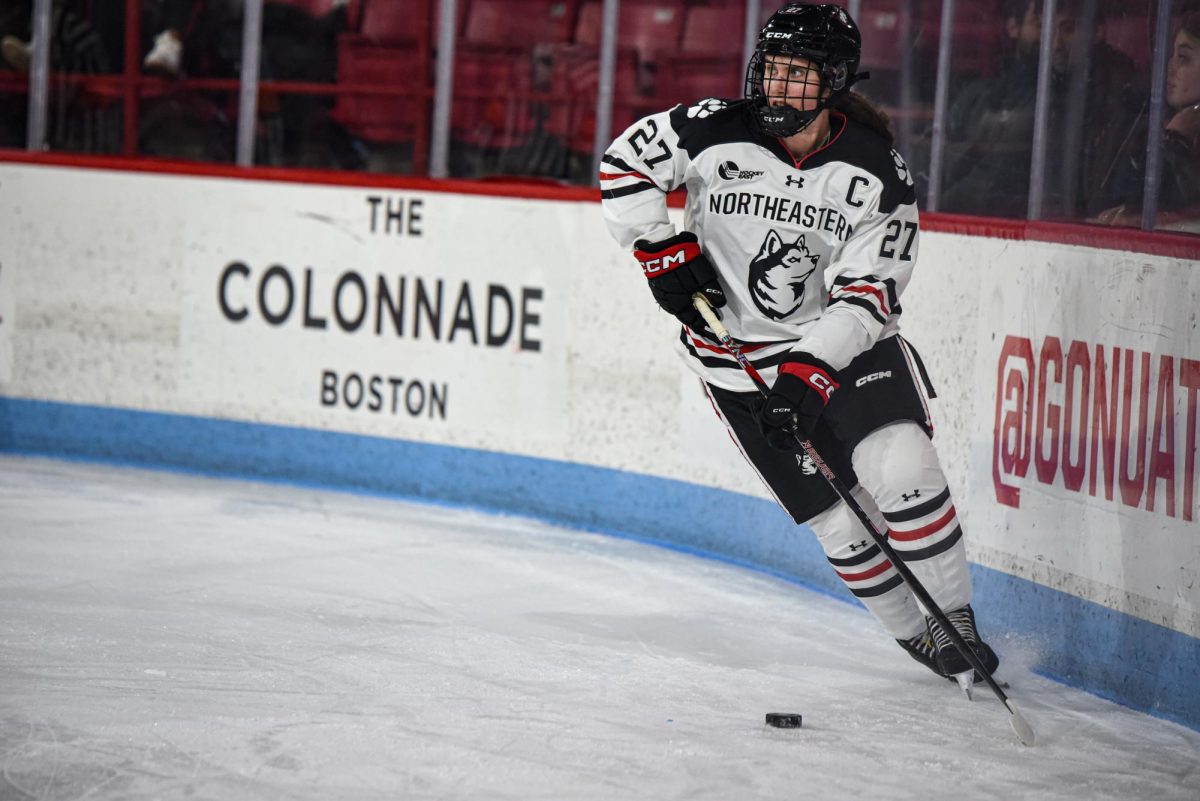 Northeastern captain Megan Carter brings the puck along the boards in a game against the University of Connecticut. Northeastern lost two straight games to the other Hockey East Huskies over the weekend. 