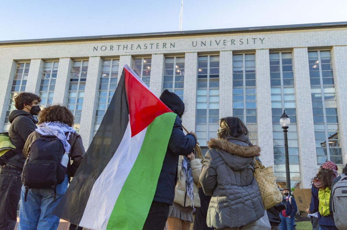 A student holds a Palestinian flag during an an emergency rally hosted by Huskies for a Free Palestine Jan. 10.